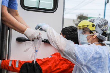 Kadın doktor, incelenmesi için bir hastaya koronavirüs testi yapıyor.