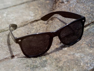 Güneşli bir havada, nemli gri bir yolda siyah güneş gözlüğü.