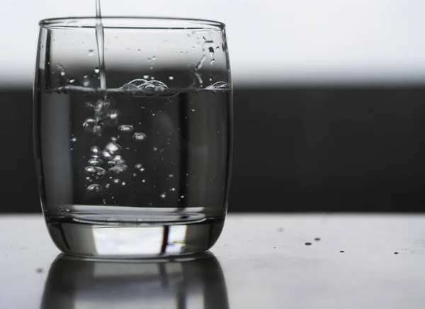 澄んだガラスの中で水を飲む灰色の背景に — ストック写真