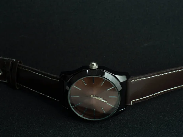 ブラックテクスチャの背景にブラウンの腕時計 — ストック写真