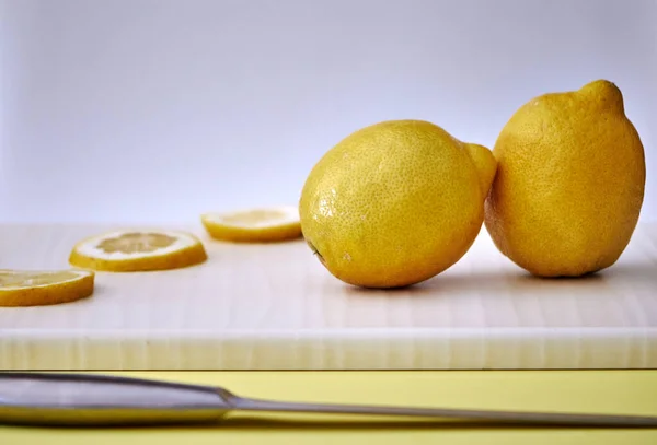 Birkaç sarı dilimlenmiş ve tüm limonlar arka planda hafif bir tahtaya yerleştirilmiş.