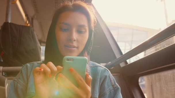 Jong gemengd ras toeristische vrouw in de Bus met behulp van mobiele slimme telefoon op luchthaven. 4k. — Stockvideo