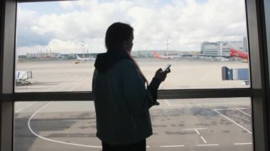 Genç kalkış Havaalanı Terminal penceresine yakınındaki cep telefonu kullanan yarış turist kadın karışık. 4k.