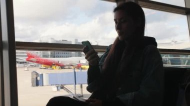 Genç kalkış Havaalanı Terminal penceresine yakınındaki cep telefonu kullanan yarış turist kadın karışık. 4k.