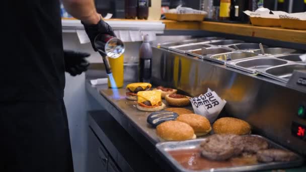 Шеф-повар плавит веганский сыр с помощью горящей пожарной плиты и делает бургер на кухне ресторана. 4K Slowmotion . — стоковое видео
