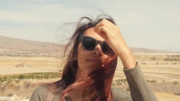 Giovane attraente sorridente ragazza mista Ritratto in un deserto. Felice turista donna in posa sulla macchina fotografica con i capelli che ondeggiano nel vento. Cappadocia, Turchia. Rallentamento 4K . — Video Stock