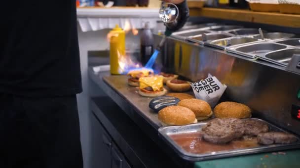 シェフを使用して火災ストーブの燃焼とレストランの厨房でハンバーガーを作るビーガン チーズを溶かします。4 k スローモーション. — ストック動画
