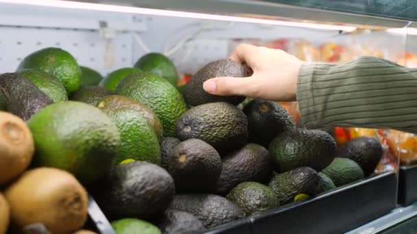 Junge Frau wählt Avocados im Lebensmittelladen. Vegane Zero-Waste-Mädchen kaufen Obst und Gemüse im Bio-Supermarkt. 4k. — Stockvideo