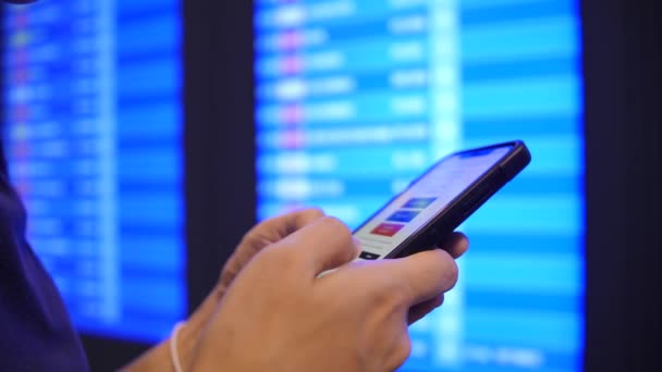 観光女性チェック彼女飛行時間を使用して携帯電話空港出発ボードに近い スローモーション バンコク — ストック動画