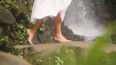 Erkek tropikal ormanda güzel doğal şelale, çıplak ayakla yürümek. Sakin ve kaygısız yaşam tarzı seyahat 4k Slowmotion görüntüleri. Bali, Endonezya.