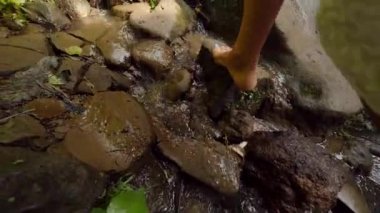 Yalınayak bir yolda küçük şelale tropikal yağmur ormanları içinde yürüyüş beyaz elbiseli Genç çekici kadın. Kaygısız yaşam seyahat 4k Slowmotion görüntüleri. Bali, Endonezya.