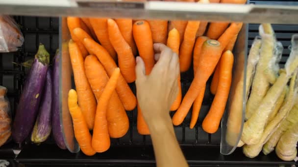 Jonge Vegan vrouw kiezen wortelen in de supermarkt. Organische fruit en groenten winkelen. 4 k. Bali, Indonesië. — Stockvideo