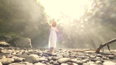 Mutlu genç yarış turist kız beyaz elbise ve hasır şapka Selfie fotoğrafları cep telefonuyla inanılmaz büyük Jungle Şelalesi ile yapma karışık. Yaşam tarzı seyahat 4k görüntüleri. Bali, Endonezya.