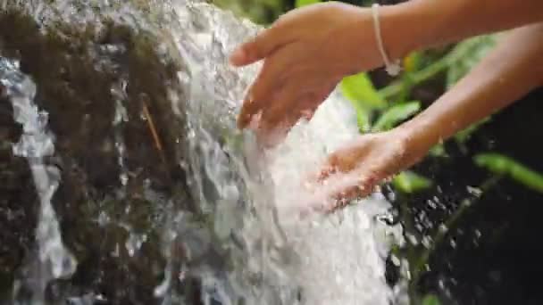 女性の手がきれいな天然の湧き水の滝ジャングルの熱帯雨林に触れます スローモーション インドネシア バリ島 — ストック動画