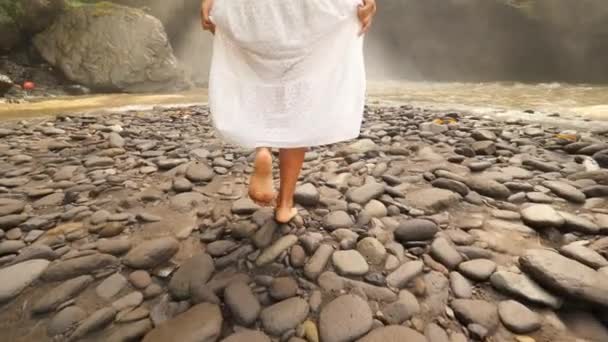 Mladá dívka v bílých šatech a slaměný klobouk pěšky do Tegenungan vodopád bezstarostný životní styl cestování 4k Slowmotion záběry. Bali, Indonésie. — Stock video