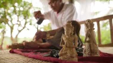 Woodcarver oyma ahşap iş parçası üzerinde keskin aletler ile yapıyor. Geleneksel Balinese heykelciği yapma işlemi. 4 k. Bali, Endonezya.