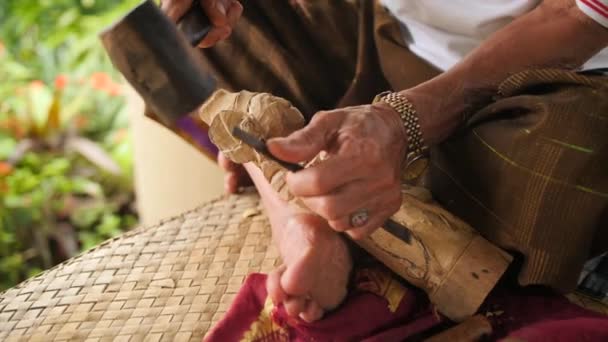 Ξυλογλύπτη κάνοντας σκάλισμα με αιχμηρά εργαλεία για ξύλινο κομμάτι προς κατεργασία. Διαδικασία λήψης παραδοσιακό μπαλινέζικο αγαλματίδιο. 4 k. Μπαλί, Ινδονησία. — Αρχείο Βίντεο