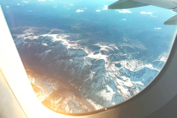 Witte wolken hemel en bergen zoals gezien door het venster van een vliegtuig. — Stockfoto