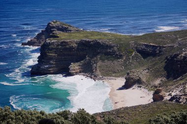 Cape Point, Güney Afrika 'daki kayalıkların altındaki güzel, el değmemiş beyaz sahil. Mavi yeşil Atlantik Okyanusu kumu kaplıyor.                             