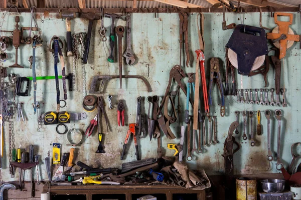 A wall of tools in an old farm shed showing both modern and vintage tools used for repairing machinery and household equipment on a property in the country.
