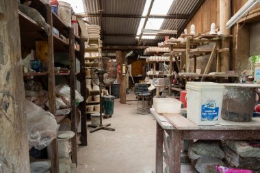 Bitmemiş yeşil eşyalarla dolu dağınık bir çömlekçi atölyesi fırına atılmayı bekliyor..