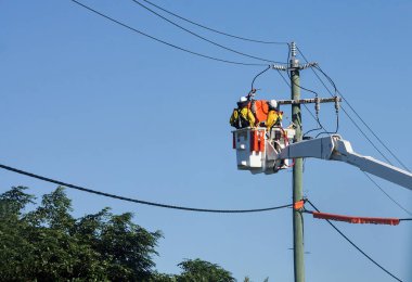 İki tamirci, elektrik direklerinin bakımını ve tamirini yapan bir kamyonun elektrik hatlarında çalışıyor..                               