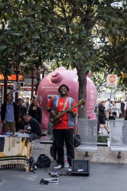 Melbourne, Avustralya 'daki yayalara gitar çalıp şarkı söyleyen bir sokak müzisyeni ya da sokak müzisyeni.