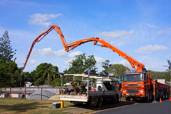 Queensland, Avustralya 'daki banliyölerde yeni bir evin temellerini atan turuncu beton pompa kamyonu
