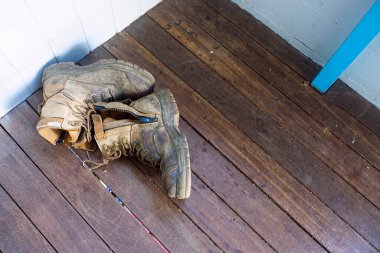 Eve toprak girmesin diye arka verandaya bırakılmış kullanılmış ve yıpranmış iş botları..