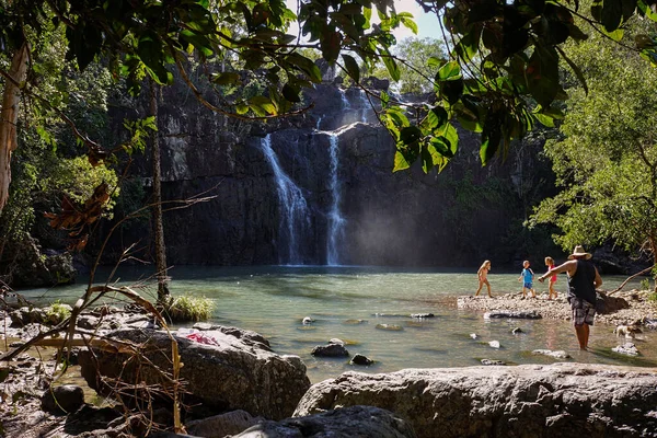 Bir aile ve köpekleri, Whitdays, Queensland, Avustralya 'daki Qirlie Sahili yakınlarındaki Cedar Creek Şelalesi' nin dibindeki havuzdaki güzel serin suyun tadını çıkarıyorlar..                             