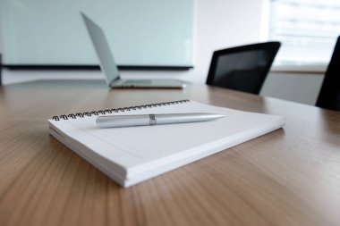 Kalem laptop ve Not defteri ve için yapılacak işler tablo boş kurumsal konferans salonunda devam etti. Seçilen odak kalem ve Not defteri.