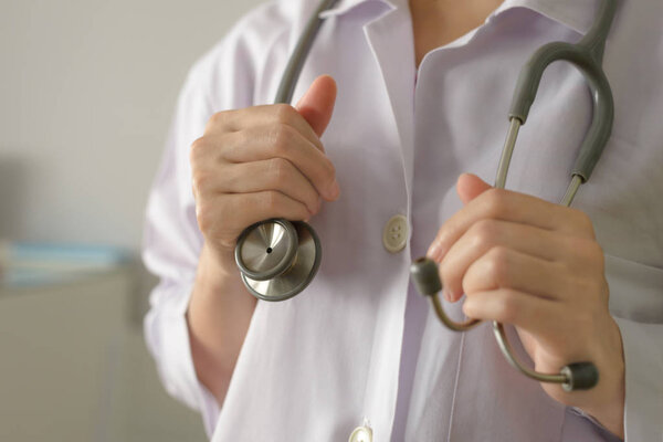 Крупный план женщины-врача, стоящей и держащей стетоскоп для проверки пациента с копировальным пространством
