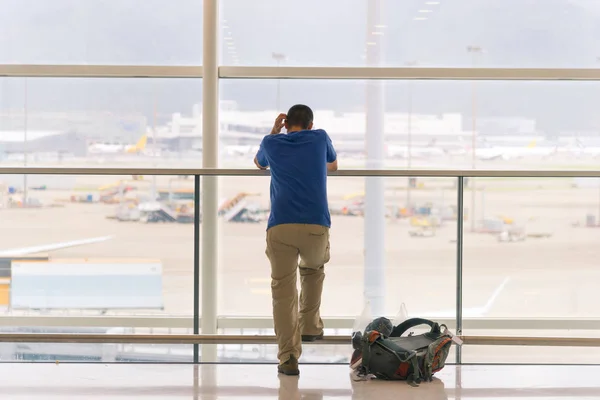 Widok z podróży człowiek stojący w pobliżu okna na Lotnisko terminal z backpacker na piętrze tyłu — Zdjęcie stockowe