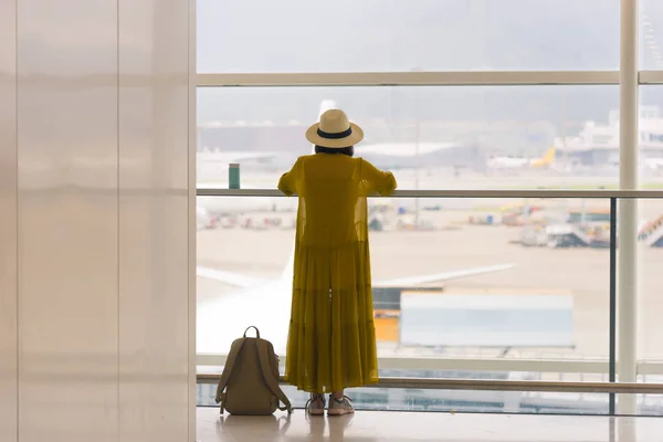 Widok z podróży dziewczynę stojącą w pobliżu okna na Lotnisko terminal z backpacker na podłodze z tyłu — Zdjęcie stockowe