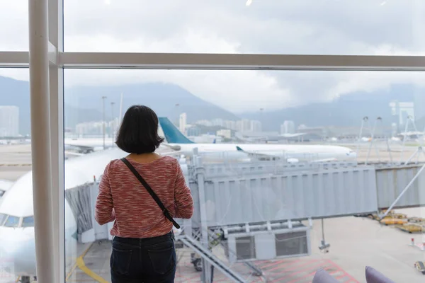Widok z podróży dziewczynę stojącą w pobliżu okna na międzynarodowym lotnisku tyłu — Zdjęcie stockowe