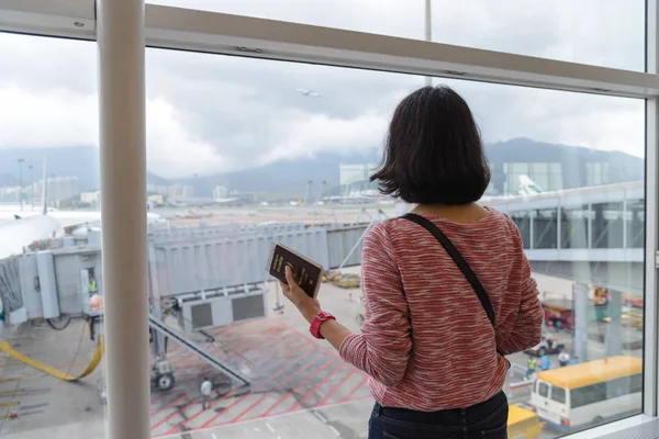 Widok z podróży dziewczyna stoi i paszportem w pobliżu okna terminalu międzynarodowego lotniska tyłu — Zdjęcie stockowe