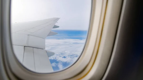 Wing of the plane flying above the clouds. View from the window of an airplane — Stock Photo, Image