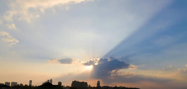 Mooie dramatische hemel wolken met licht die stralen worden over de stad bij zonsondergang tijd. Natuurlijke landschap voor achtergrond — Stockfoto