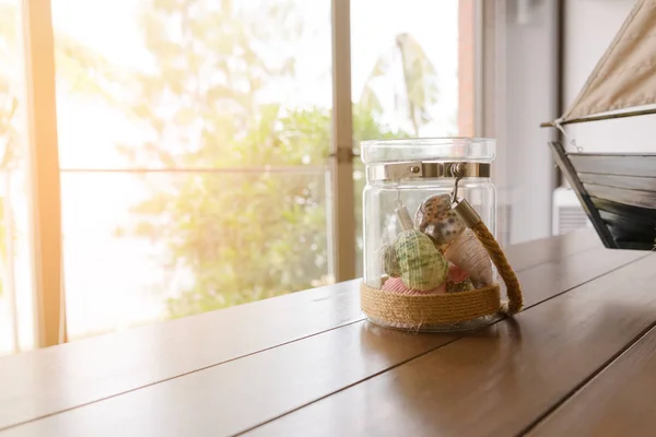 Variedad de conchas marinas en tarro de vidrio sobre mesa de madera con espacio para copiar en sala de estar. concepto de vacaciones —  Fotos de Stock