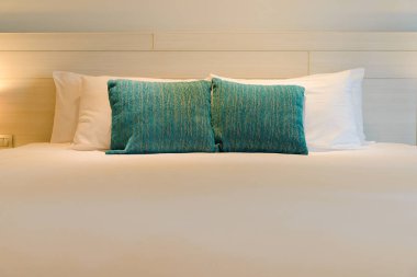 yatağa yastık istifleme, ahşap yatak başı ile beyaz yatak çarşafları