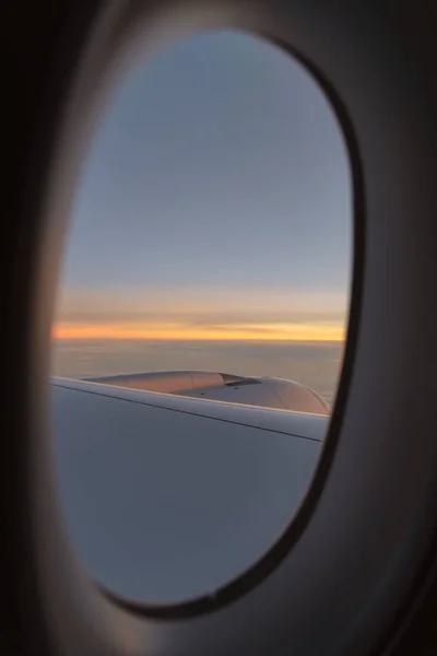 Vista dal finestrino dell'aereo che vola sopra le nuvole al tramonto — Foto Stock