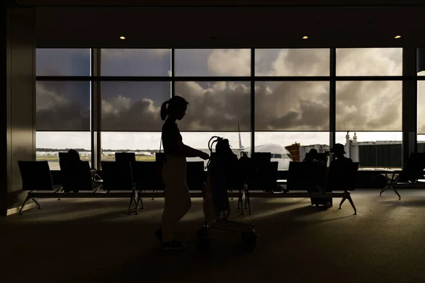 Sylwetki kobiet z wózków bagażowych w poczekalni lotniska wylotu — Zdjęcie stockowe