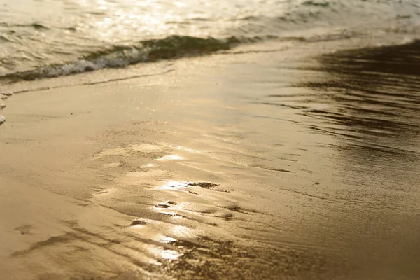 Goldenes Licht, das eine Wasserwelle am Meer und Sand bei Sonnenuntergang reflektiert. reines Gold — Stockfoto