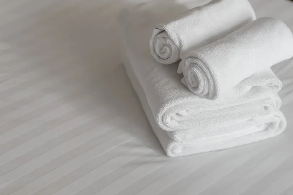 Fehér bolyhos törülközők az ágyon a szállodai hálószobában. Közeli nézet — Stock Fotó