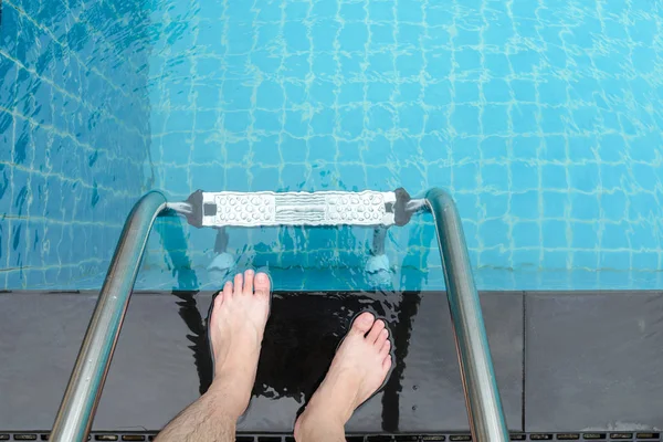 Homme debout sur le bord de la piscine allant à l'échelle en métal pour l'entrée de la piscine . — Photo