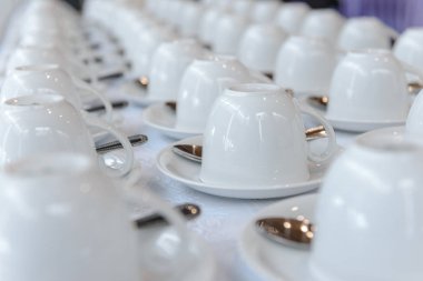 Seminer etkinliğinde veya toplantı odasında servis kahvesi veya çay için kaşıklı birçok boş bardak grubu