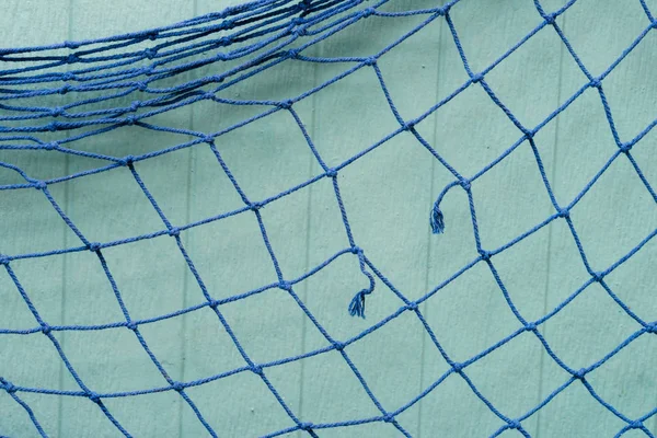 Blue fishing net hanging on wood wall — Stock Photo, Image