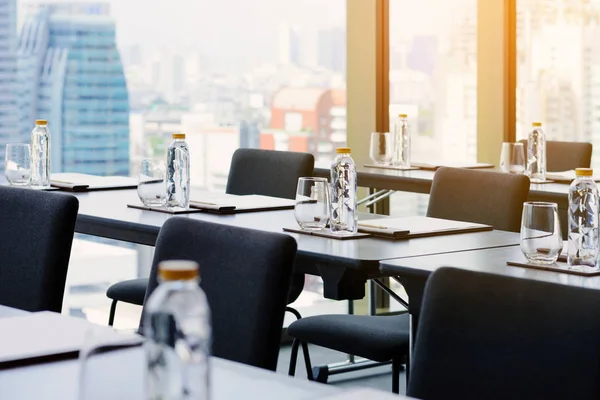 Plastic water bottles, Drinking glasses with pencil and white papers setup on the table prepared for seminar or business meeting in the hotel conference room