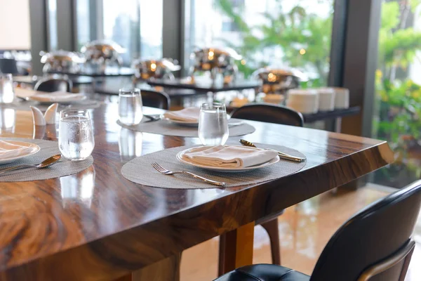 Vajilla en el restaurante. Mesa elegante decorada, platos de porcelana, vasos, servilleta, cuchillo, tenedor y cuchara en mesa de madera — Foto de Stock