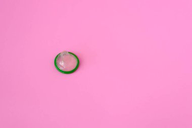 Pembe kağıdın üzerine yeşil prezervatif ve metin için fotokopi alanı. Üreme sağlığı ve güvenli seks kavramı